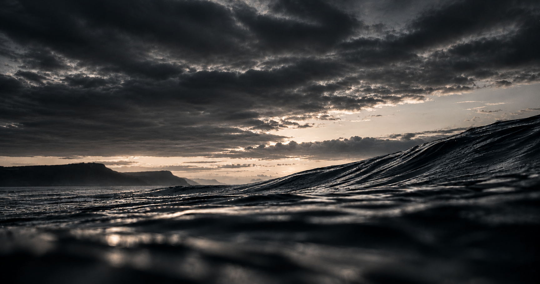 Dark stormy sea with distant cliffs under dramatic clouds